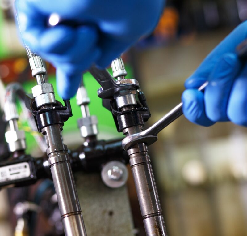 Professional mechanic testing diesel injector in his workshop.