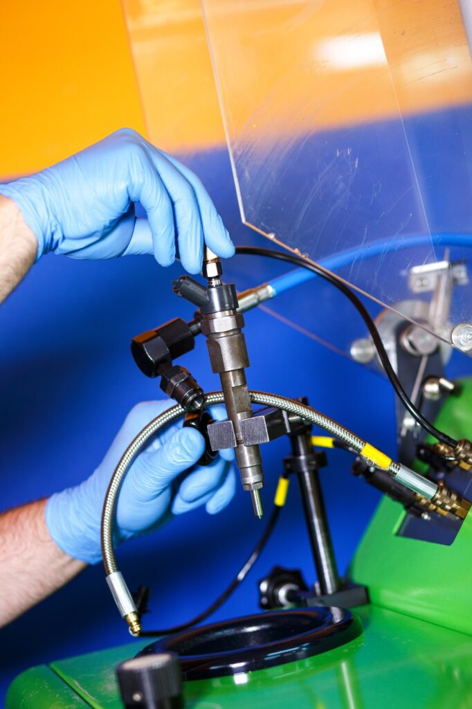 Professional mechanic testing diesel injector in his workshop.